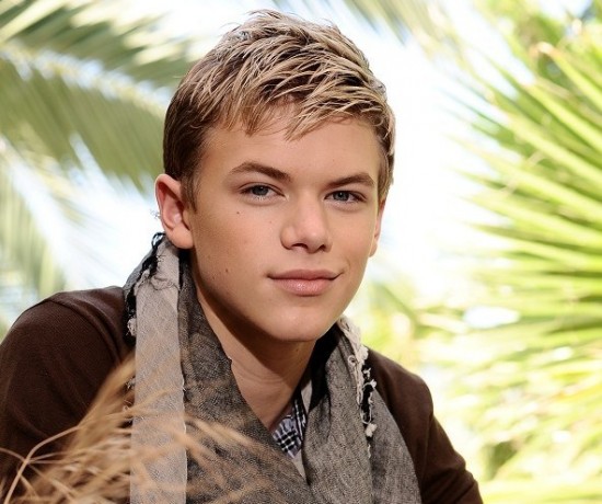 A young man, Kenton Duty, in a scarf posing in front of a palm tree.