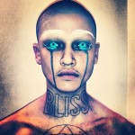 A man with blue eyes and a tattoo on his face.