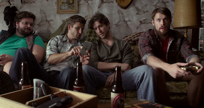 A group of men sitting on a couch at Outfest, with beer bottles.