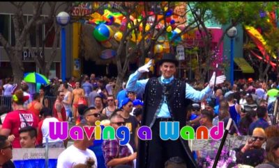 A man in a costume waving a wand in a crowd.